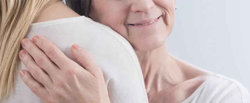 Mujer mayor abrazando a cuidadora